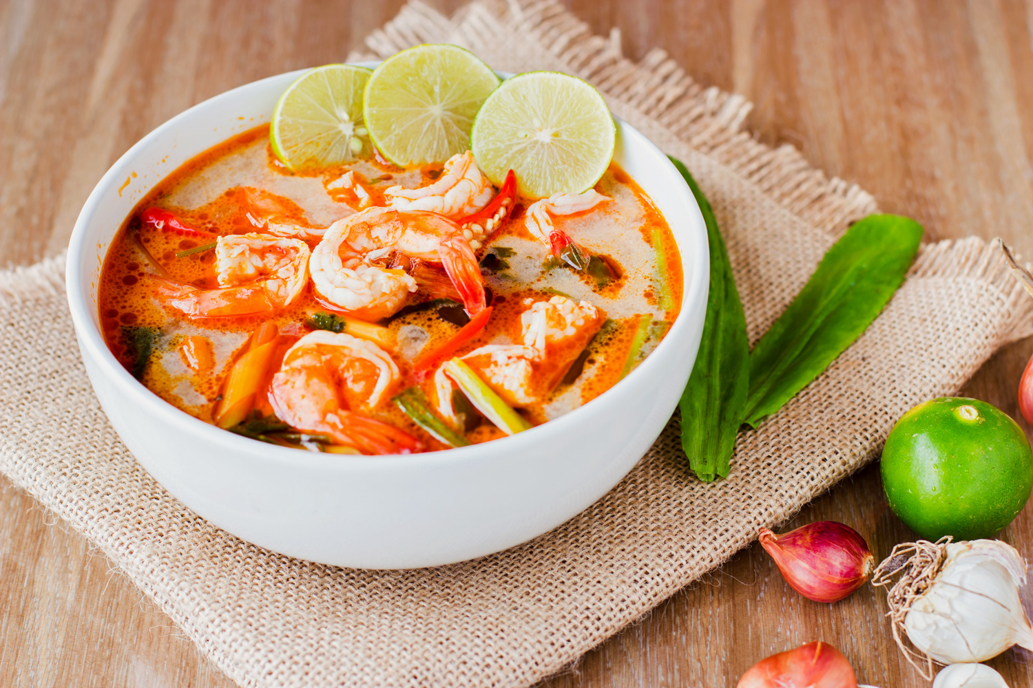 Semangkuk Tom Yum yang segar dan pedas, dengan udang besar, jamur, dan rempah segar, siap untuk dinikmati