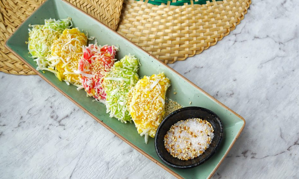 Mung bean rice crepe in red, green and yellow colours with coconut shredded topping