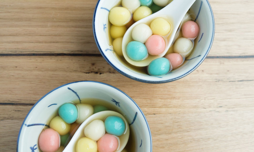 Colourful tang yuan in pink, white, blue and yellow in a brown ginger palm sugar syrup soup