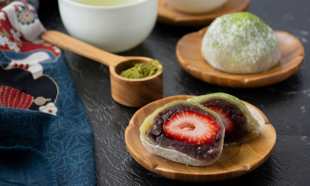 Red bean mochi cut in half to reveal strawberry and red bean paste inside