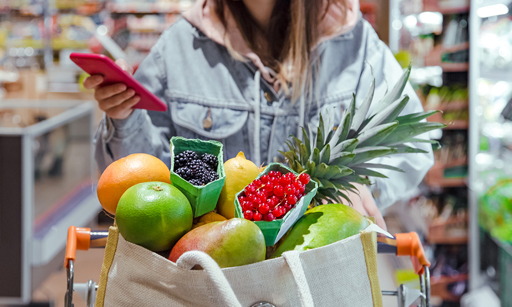 Woman wheeling grocery cart of vegetables