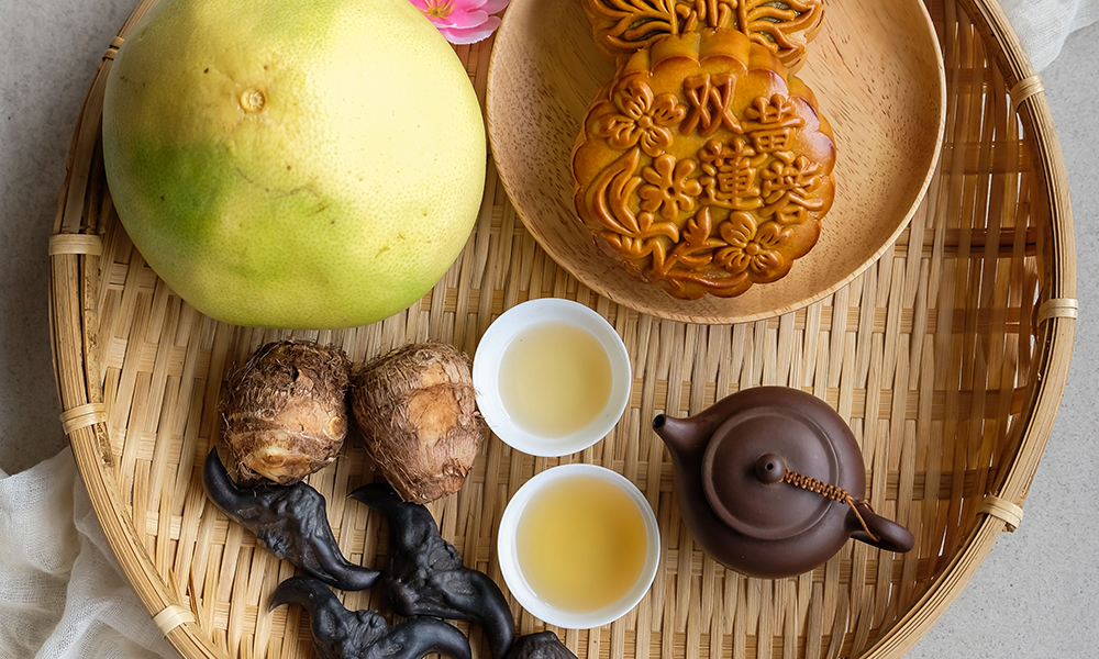 Pomelo, moon cake and tea on a wooden platter for Moon Festival